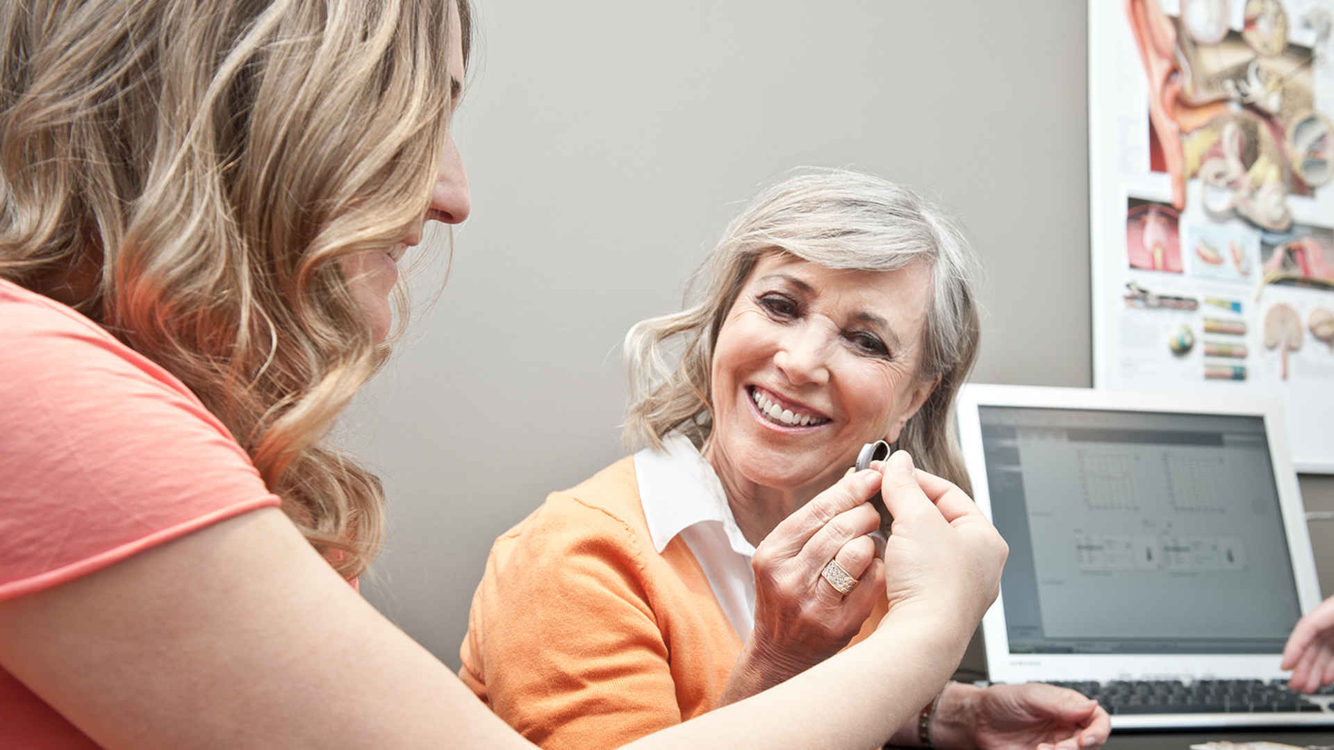 Hearing aid professional showing hearing aid to a woman