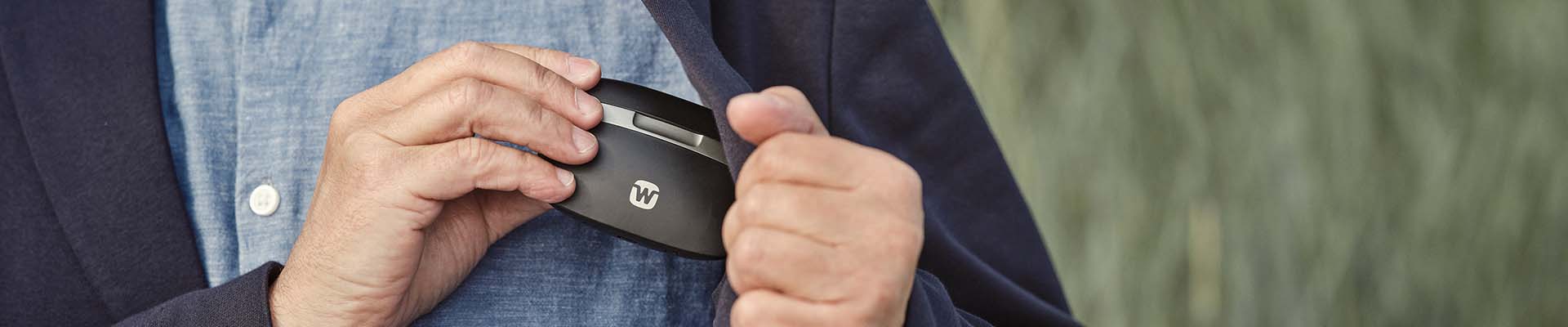 Man putting Widex portable hearing aid charger in his jacket pocket