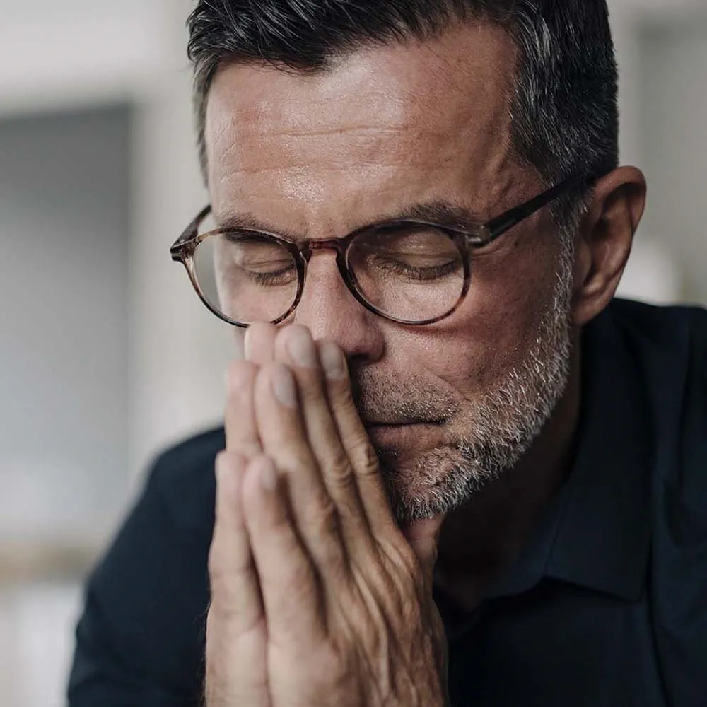 Man with closed eyes, hands on face