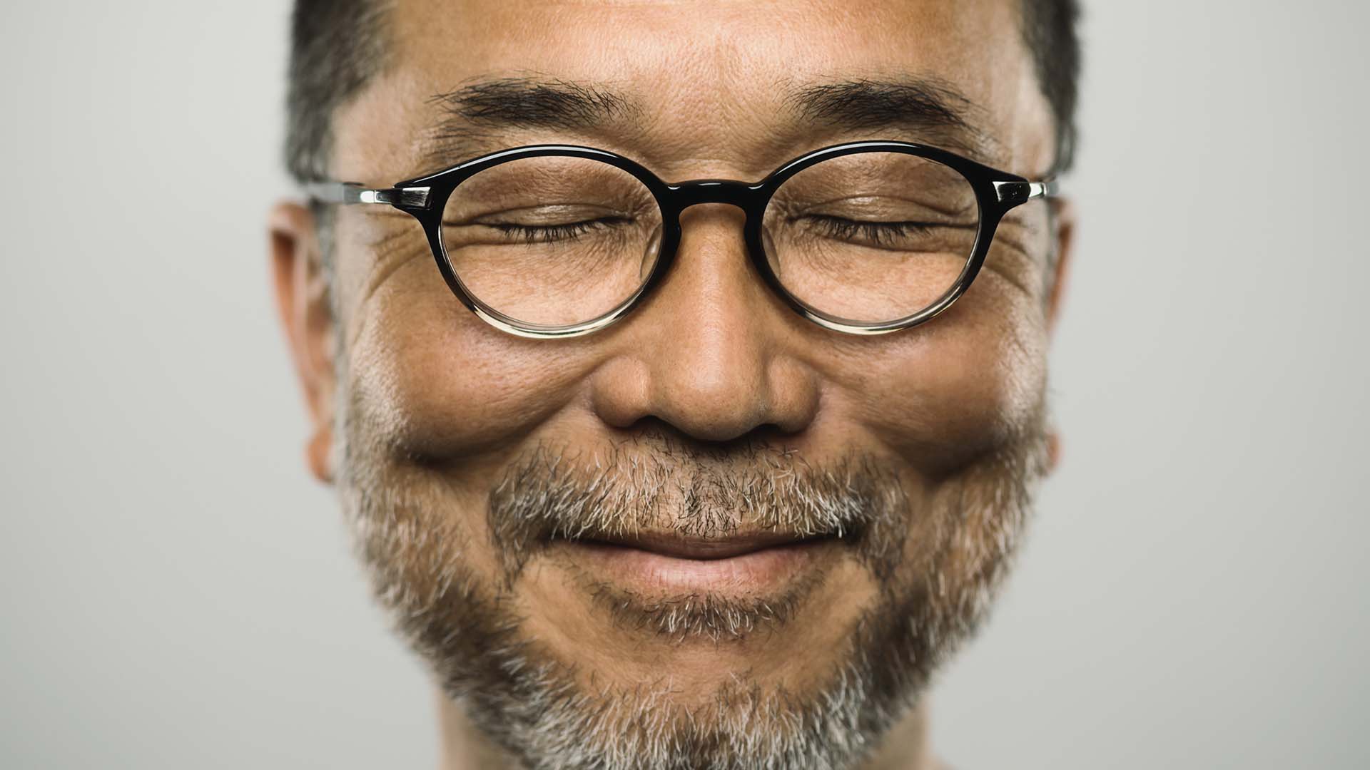 Man with glasses and closed eyes is smiling