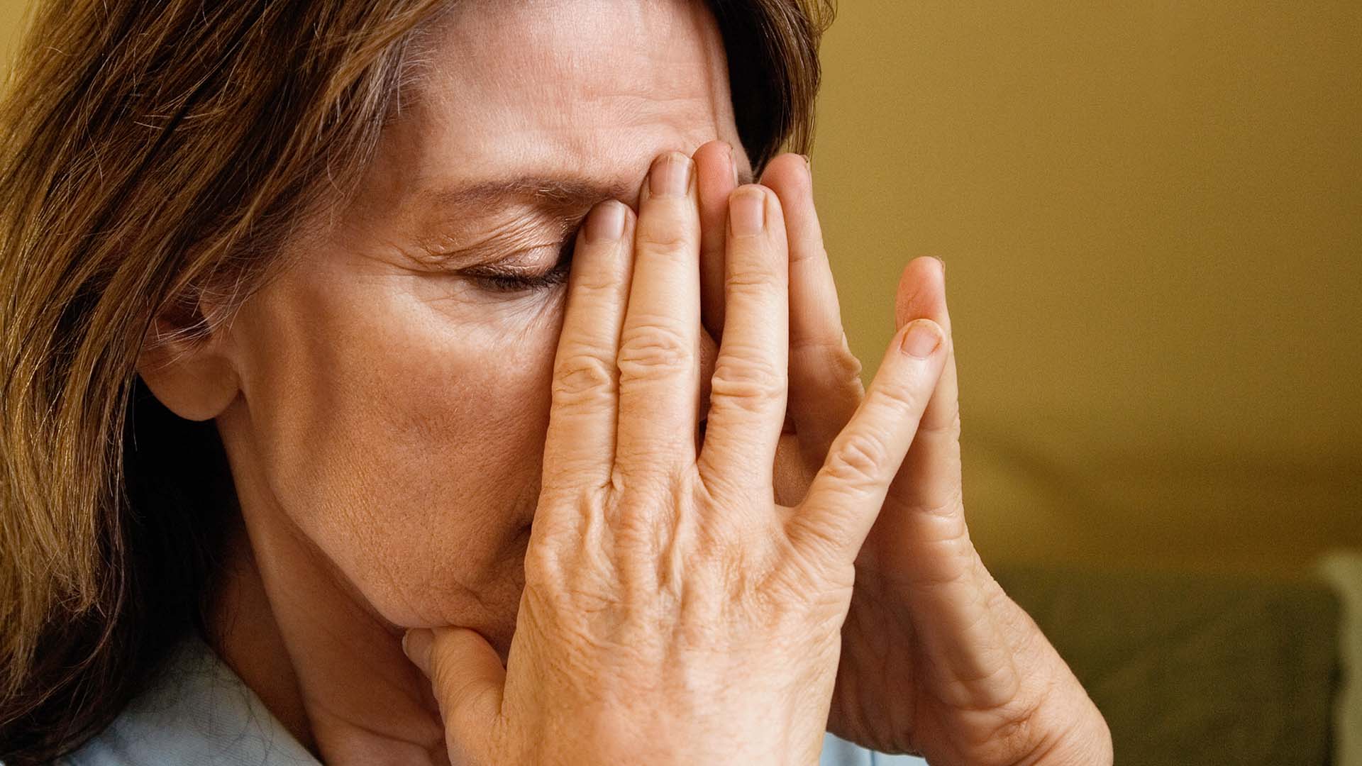Stressed woman, covering face with hands